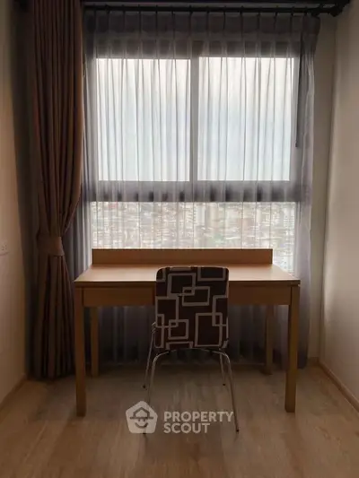 Cozy study area with desk and chair by a large window with city view.