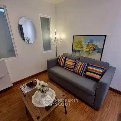 Charming living room with cozy sofa, vibrant cushions, elegant chandelier, and modern decor.