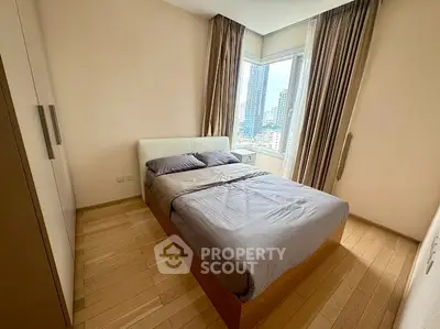 Cozy bedroom with city view, featuring a comfortable bed and elegant curtains.