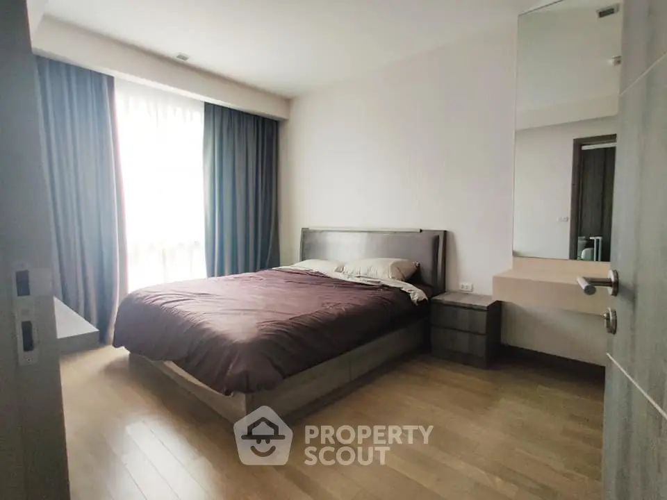 Spacious bedroom with modern furnishings and large window for natural light.