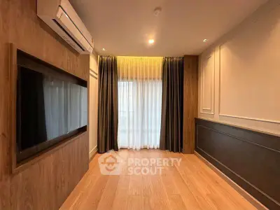 Spacious modern living room with wood flooring and large window, featuring elegant curtains and wall-mounted air conditioning.