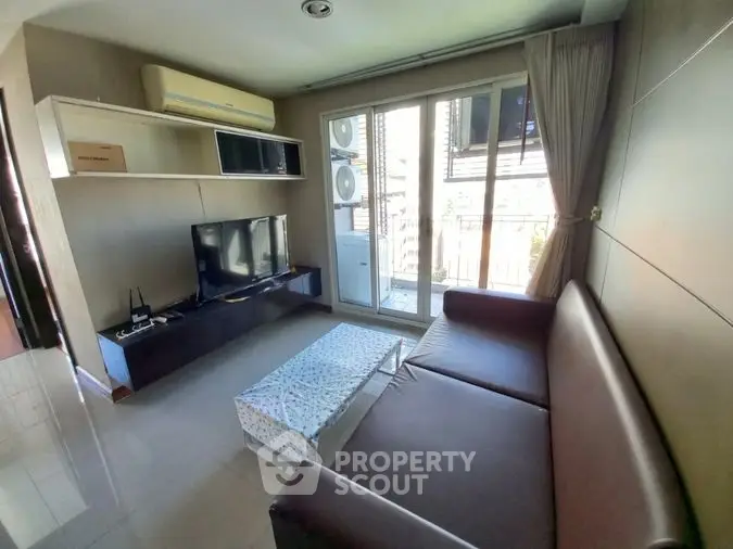 Sunlit cozy living room with modern furnishings, featuring a comfortable brown sofa, sleek TV unit, and balcony access for an airy ambiance.
