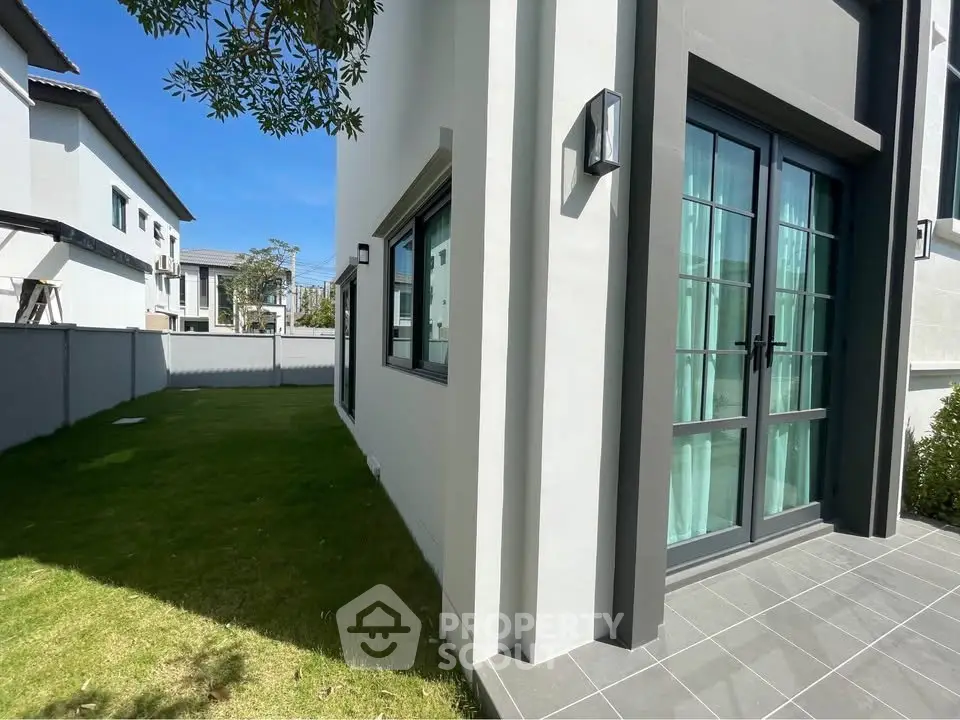 Modern house exterior with lush green lawn and stylish glass doors