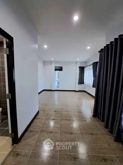 Spacious modern living room with elegant tile flooring and ample natural light.