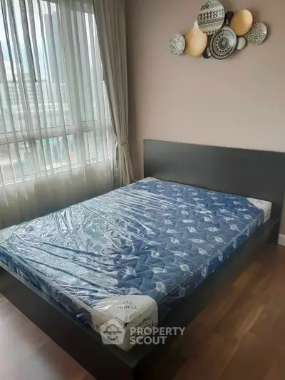 Modern bedroom with large window and stylish decor in a high-rise apartment.