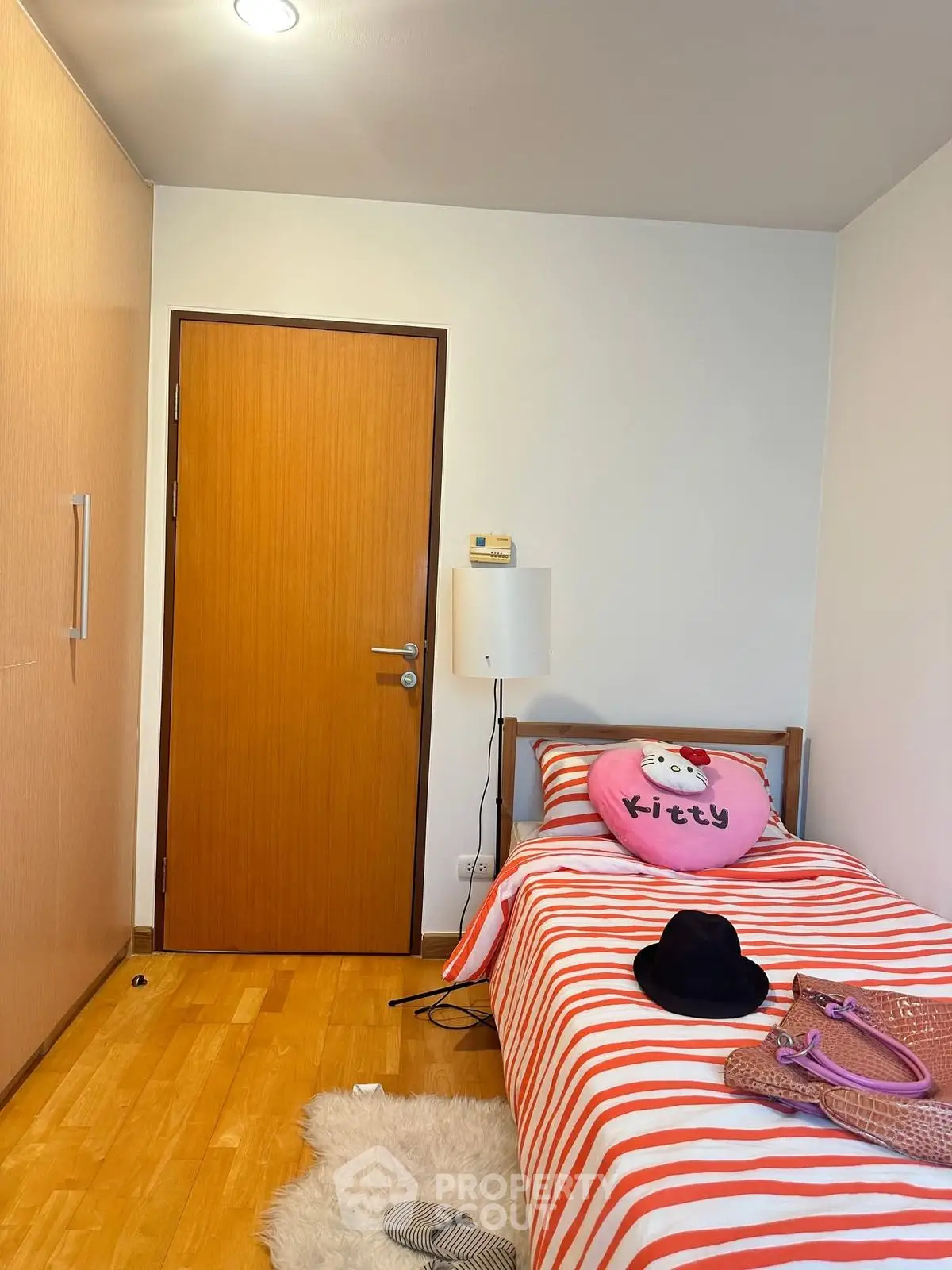 Cozy bedroom with single bed, wooden flooring, and closet, ideal for a child's room.