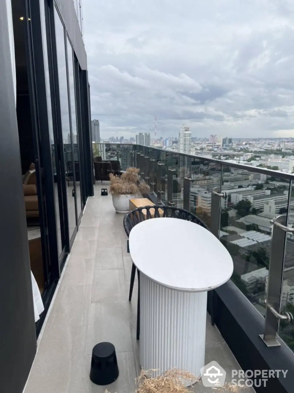 Stunning high-rise balcony with panoramic city views and modern outdoor furniture.