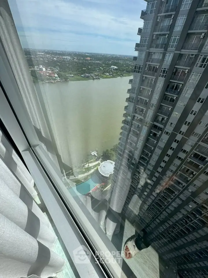 Stunning high-rise apartment view overlooking river and cityscape, perfect for urban living enthusiasts.
