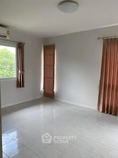 Spacious empty room with tiled floor and large windows, ideal for customization.