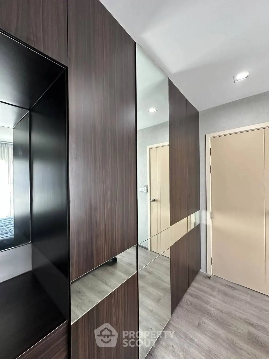 Modern hallway with sleek wooden paneling and mirrored accents in a contemporary apartment.