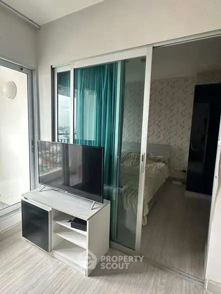 Modern bedroom with sliding glass doors and TV stand, featuring a cozy bed and stylish decor.