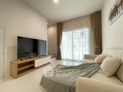 Modern living room with large TV and cozy sofa, featuring elegant curtains and natural light.