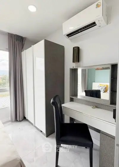 Modern bedroom with sleek furniture and air conditioning, featuring a stylish vanity and wardrobe.