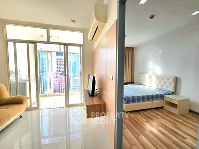 Modern apartment with bright living area and cozy bedroom, featuring a balcony with city views.