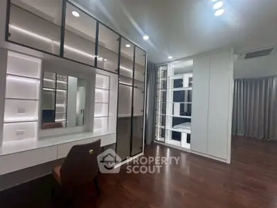 Luxurious modern bedroom with elegant built-in wardrobe and vanity area, featuring sleek lighting and hardwood floors.