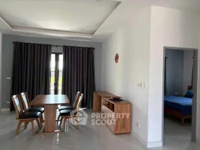 Spacious dining area with wooden furniture and view into a cozy bedroom, perfect for modern living.
