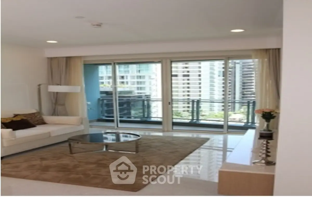 Modern living room with large windows and city view, featuring elegant decor and spacious layout.