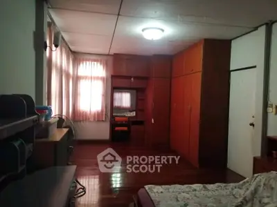 Spacious bedroom with wooden flooring and ample storage space