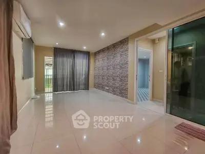 Spacious living room with modern tile flooring and accent brick wall, perfect for stylish living.