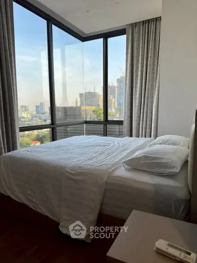 Luxurious bedroom with floor-to-ceiling windows offering stunning city views.
