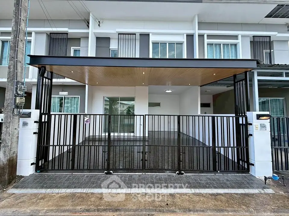 Modern townhouse exterior with sleek black gate and covered parking area