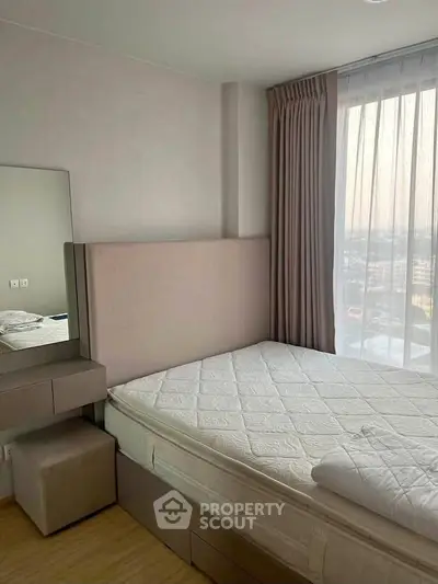 Cozy bedroom with large window offering city views, featuring a comfortable bed and elegant curtains.