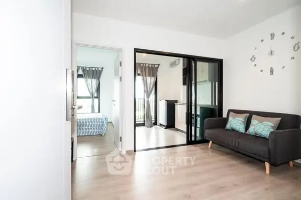 Modern apartment with open living room and bedroom, featuring sleek design and natural light.