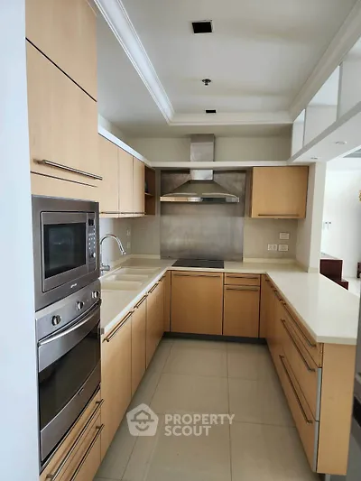 Modern kitchen with sleek wooden cabinets and built-in appliances in a contemporary home.