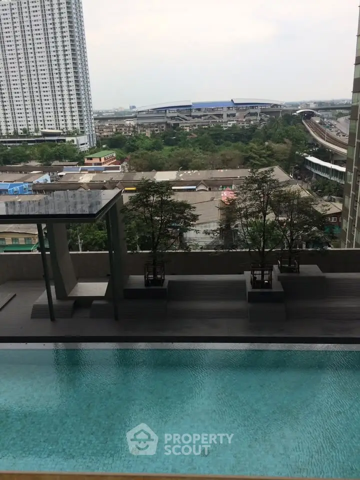 Stunning urban view from a high-rise building with a serene pool and lush greenery.