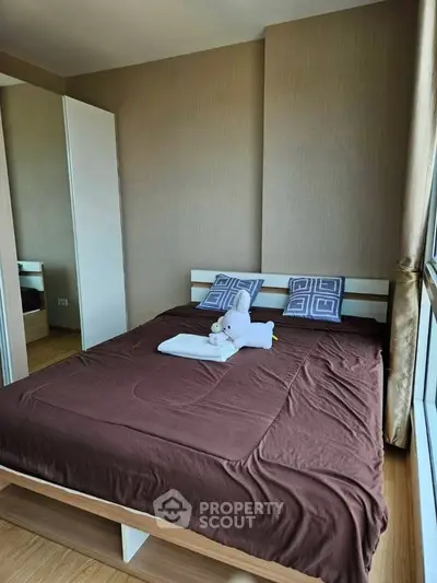 Cozy bedroom with modern decor and large window offering natural light.