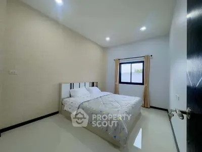 Modern bedroom with minimalist decor and large window for natural light.