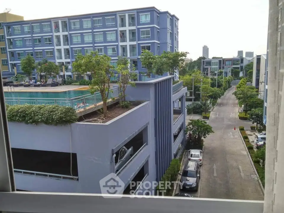 Modern apartment complex with pool and parking view, showcasing urban living.