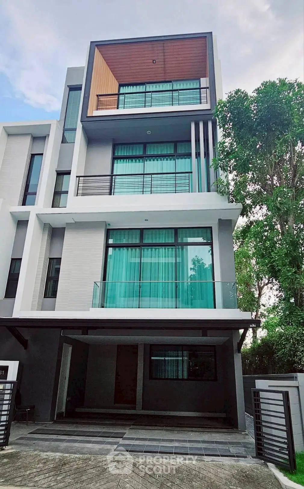 Modern multi-story house with large windows and sleek design in a serene neighborhood.