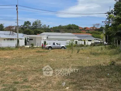 Spacious plot of land with modern houses in the background, ideal for development opportunities.