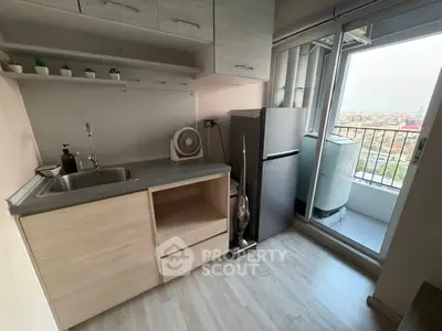 Compact kitchen with balcony view, featuring modern appliances and sleek cabinetry.