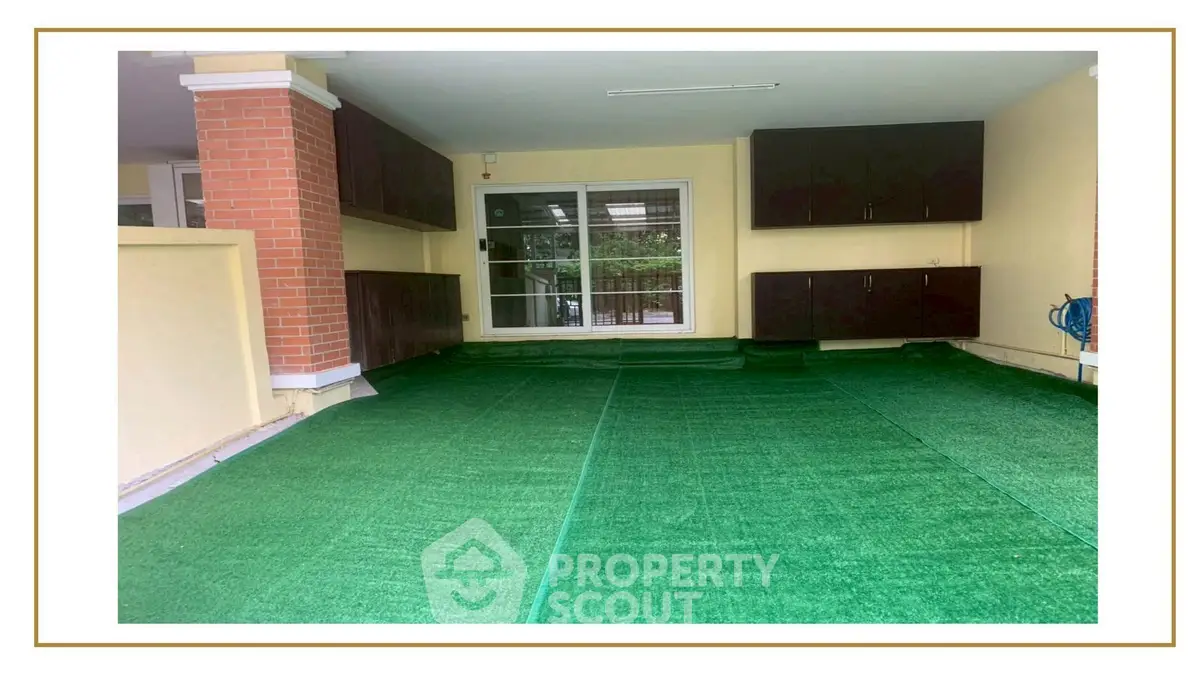 Spacious covered parking area with artificial grass flooring and storage cabinets.