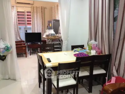 Cozy dining area with wooden table and chairs, adjacent to a living room with TV and air conditioning.