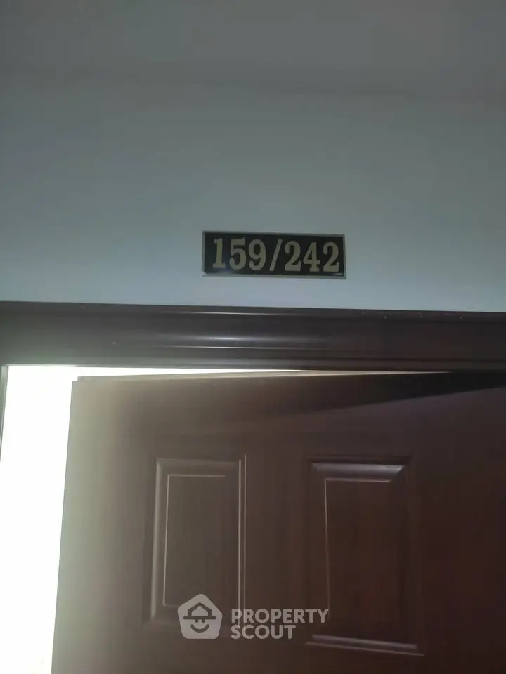 Apartment entrance with door number 159/242, showcasing a wooden door frame.