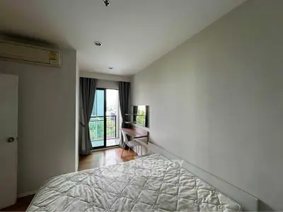 Modern bedroom with balcony access and study area in a bright apartment.
