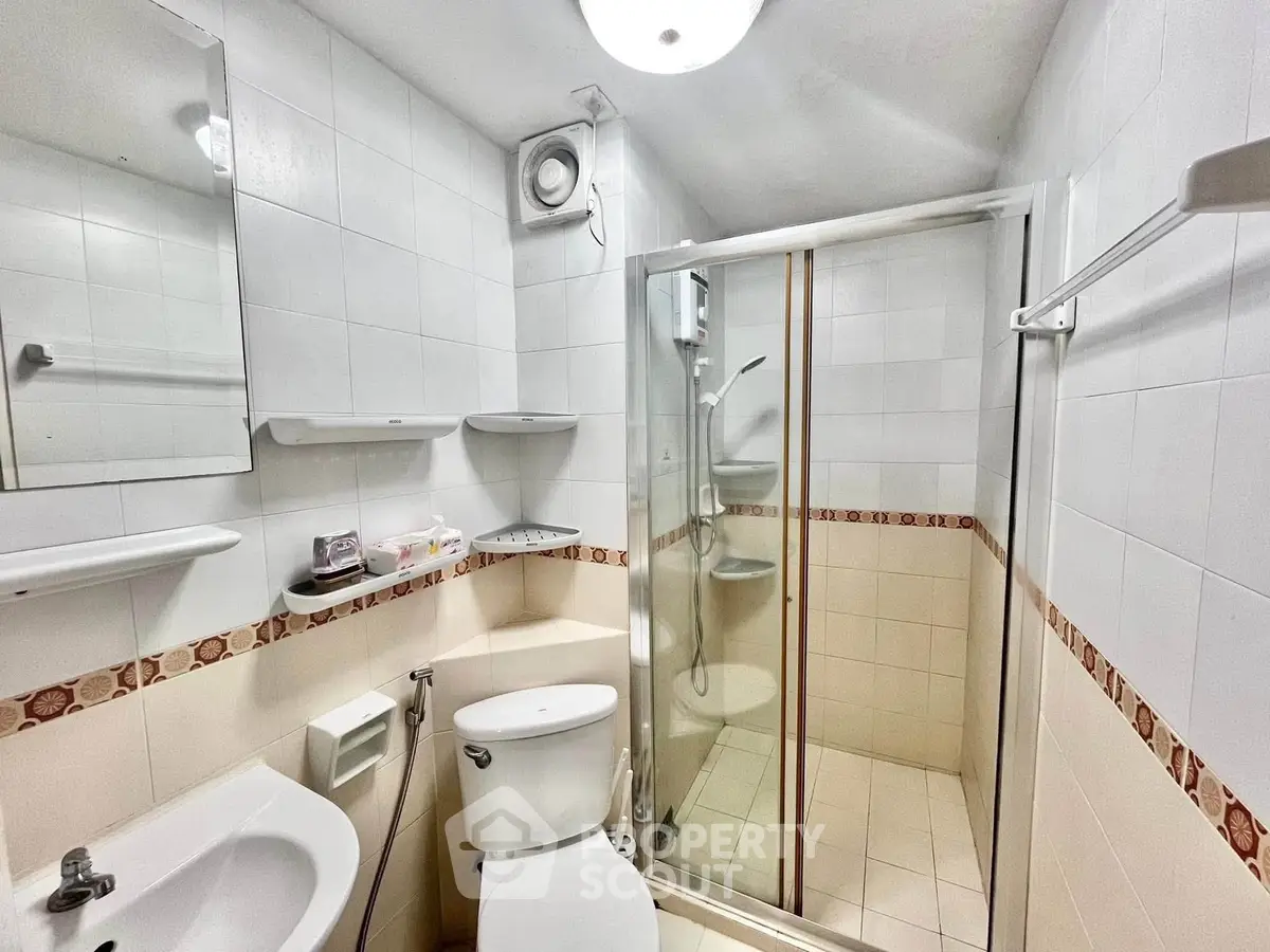Compact bathroom with shower, toilet, and sink in a modern apartment.