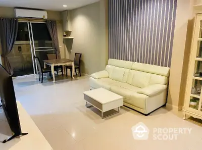 Spacious living room with gleaming tiled floors, modern furniture, and sliding doors leading to a well-lit balcony area, perfect for entertaining.