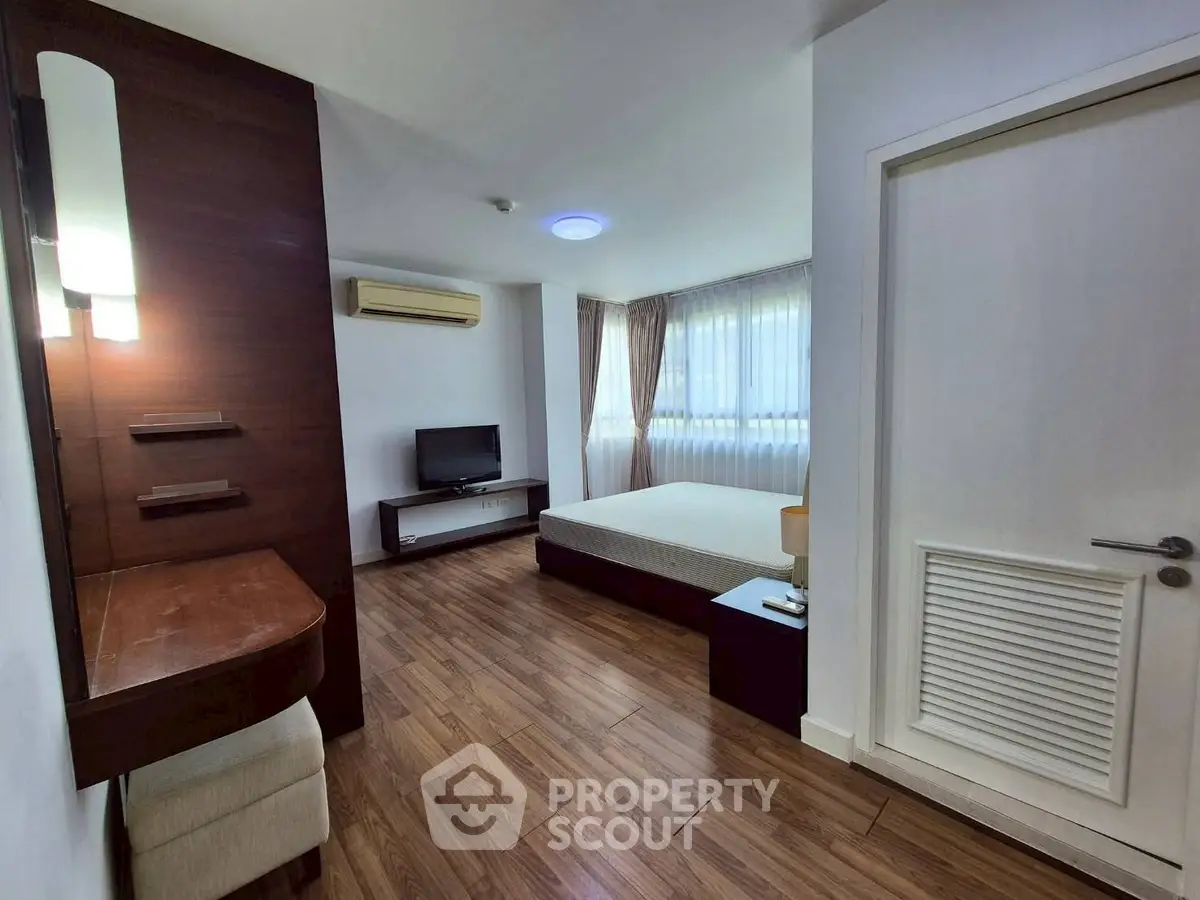 Spacious bedroom with modern furnishings and natural light, featuring hardwood floors and a cozy ambiance.