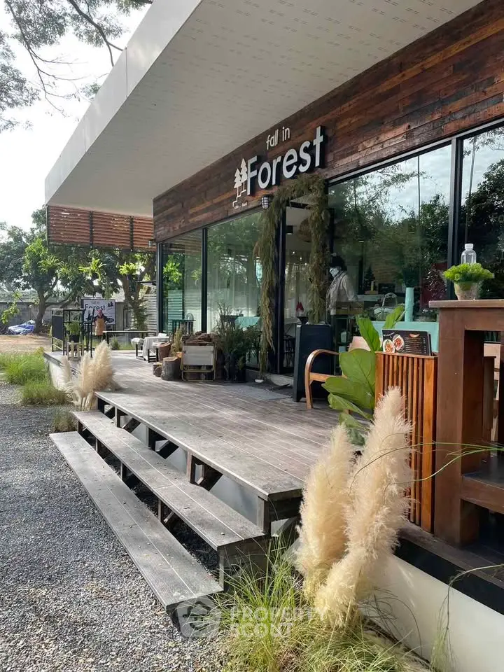Charming modern cafe with wooden deck and lush greenery, perfect for relaxation and gatherings.
