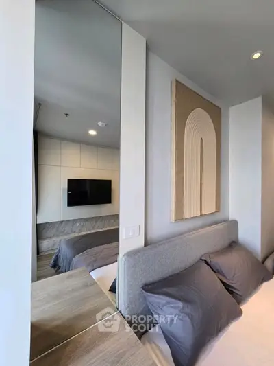 Modern bedroom with stylish decor and wall-mounted TV, featuring cozy bedding and contemporary artwork.