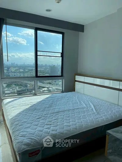 Spacious bedroom with stunning city view and large window.