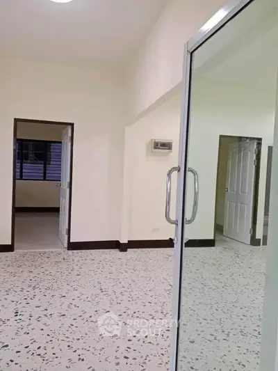 Spacious interior with terrazzo flooring and glass door, ideal for modern living.