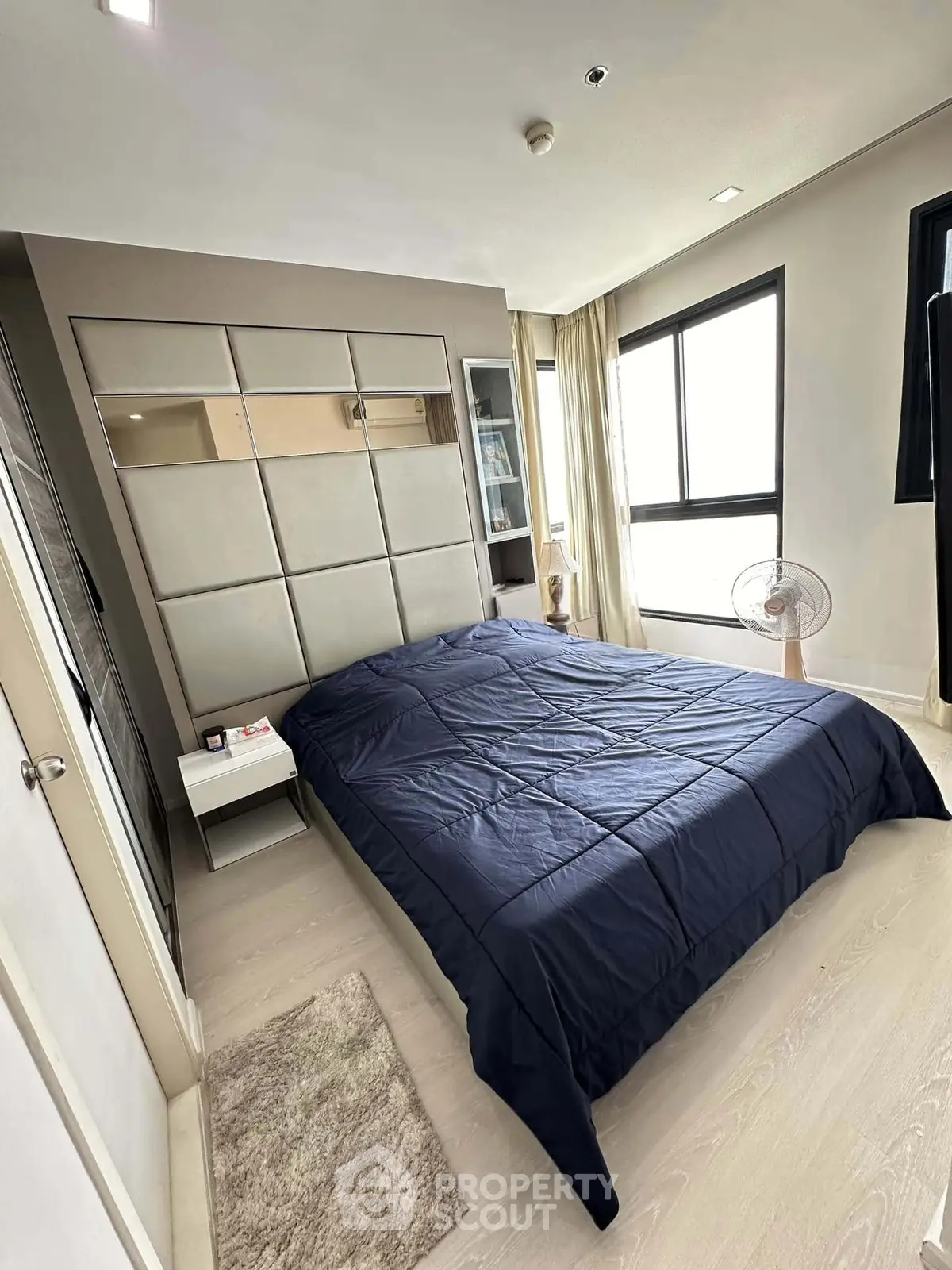 Modern bedroom with stylish decor and large windows offering natural light