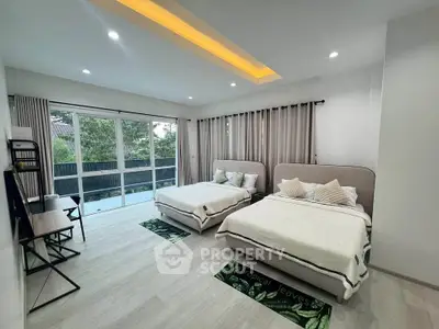 Spacious bedroom with two beds and large windows offering a serene view, perfect for relaxation.