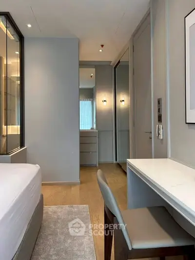 Modern bedroom with sleek design, featuring a comfortable bed, stylish desk, and elegant lighting.