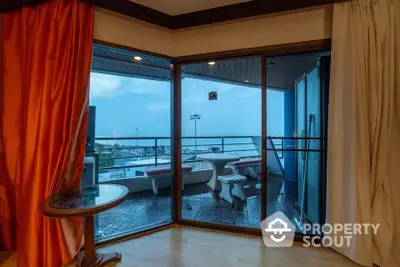 Stunning ocean view from modern balcony with elegant curtains and cozy seating area.